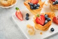 Phyllo or filo pies with fresh berries strawberries and blueberries, cheese filling topped with fresh mint on white plate. Homemad