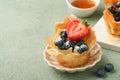 Phyllo or filo pies with fresh berries strawberries and blueberries, cheese filling topped with fresh mint on white plate. Homemad