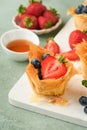 Phyllo or filo pies with fresh berries strawberries and blueberries, cheese filling topped with fresh mint on white plate.