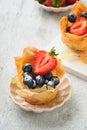 Phyllo or filo pies with fresh berries strawberries and blueberries, cheese filling topped with fresh mint on white plate.