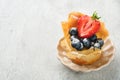 Phyllo or filo pies with fresh berries strawberries and blueberries, cheese filling topped with fresh mint on white plate.