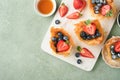 Phyllo or filo pies with fresh berries strawberries and blueberries, cheese filling topped with fresh mint on white plate.