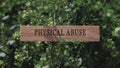 physical abuse . Written on wooden surface. Background tree leaves. Health and social problems.