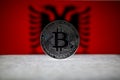 Physical silver version of Bitcoin BTC and Albania Flag on the background. Conceptual image for investors in