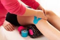 Physical therapist applying kinesio tape on female patients knee. Close up cropped shot. Kinesiology, physical therapy.