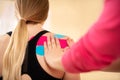 Physical therapist applying kinesio tape on female patients shoulder. Close up rear view. Kinesiology, physical therapy. Royalty Free Stock Photo