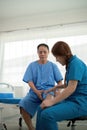 Physical therapist Asian woman, doing leg physiotherapy for elderly man to treat osteoarthritis and nerve pain in the Royalty Free Stock Photo