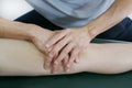 Physical therapist hands treat the knee to the patient on bed.