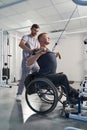 Physical therapist help wheelchair patient in gym. Man with paraplegia Royalty Free Stock Photo