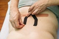 Physical therapist placing kinesio tape on patient s back