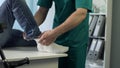 Physical therapist putting cast gypsum on patients broken leg, trauma treatment