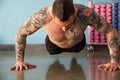 Personal trainer with tattoos performs exercises with his arms raised off the floor