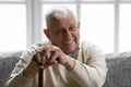 Positive old grandfather holding walking stick resting on couch