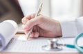 Physician doctor writing on medical health care record, patients discharge, or prescription form paperwork in hospital clinic Royalty Free Stock Photo