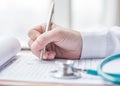 Physician doctor writing on medical health care record, patients discharge, or prescription form paperwork in hospital clinic Royalty Free Stock Photo