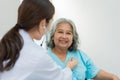 Physician examining heart with a stethoscope and talking with a senior woman at a clinic for check yearly checkup, Medicine health