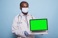Physician holds laptop with green screen