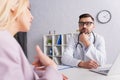 physician looking at blurred woman talking
