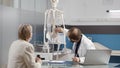 Physician pointing at human skeleton to explain osteopathy diagnosis