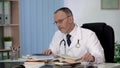 Physician reading medical books searching information about rare disease science Royalty Free Stock Photo