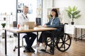 Physician with tablet sitting near lady with disability