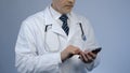 Physician typing message on cellphone, online consultation, modern technologies