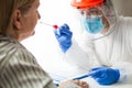 Medical worker in personal protective equipment wearing face shield performing PCR COVID-19 nasal swab test