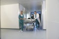 Physicians Moving Patient On Gurney Through Hospital Corridor