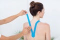Physiotherapist applying blue kinesio tape to patients back