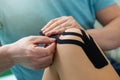 Physiotherapist applying kinesiology tape to patient knee. Royalty Free Stock Photo