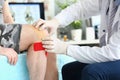 Physiotherapist applying kinesiotape to patient knee in clinic closeup