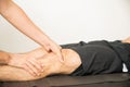 Physiotherapist Applying Pressure To Massage Young Man`s Knee