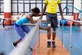 Physiotherapist assisting disabled man walk with parallel bars in sports center