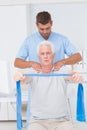 Physiotherapist assisting senior man in exercising with resistance band