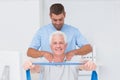 Physiotherapist assisting senior patient in exercising with resistance band