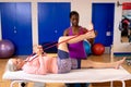 Physiotherapist assisting woman to exercise with resistance band in sports center