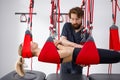 Physiotherapist assists female patient undergoing rehabilitative physiotherapy on a suspension rope system. Royalty Free Stock Photo