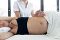 Physiotherapist doing belly massage to beautiful pregnant woman in spa center Royalty Free Stock Photo