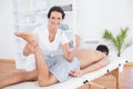 Physiotherapist doing leg massage and smiling at camera Royalty Free Stock Photo