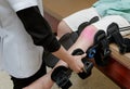 Physiotherapist fixing knee braces on patient`s leg