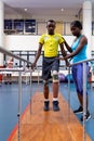 Physiotherapist helping disabled man walk with parallel bars in sports center Royalty Free Stock Photo