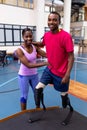 Physiotherapist helping disabled man walk with prosthetic leg on ramp in sports center