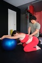 Physiotherapist helping pregnant woman to do Pilates exercises with a ball. Royalty Free Stock Photo