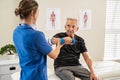 Physiotherapist helping senior man exercise