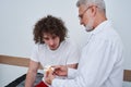 Physiotherapist holds anatomical bone model, during physiotherapy session with patient