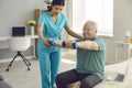 Physiotherapist or home care nurse helping senior patient do rehabilitation exercise