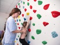 physiotherapist instructor helping little girl to climb wall in gym. sensory integration for kid and correctional Royalty Free Stock Photo