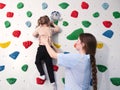 physiotherapist instructor helping little girl to climb wall in gym. sensory integration for kid and correctional Royalty Free Stock Photo