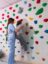 physiotherapist instructor helping little girl to climb wall in gym. sensory integration for kid and correctional Royalty Free Stock Photo