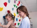 physiotherapist instructor helping little girl to climb wall in gym. sensory integration for kid and correctional Royalty Free Stock Photo